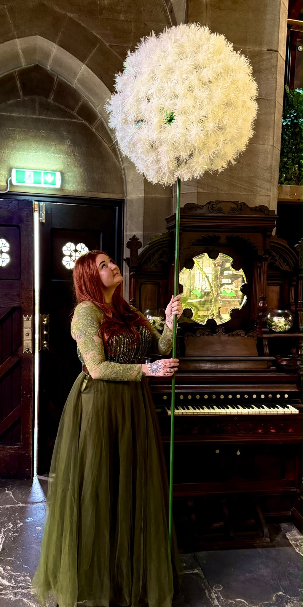 A performer in a green dress holding a large white balloon sculpture