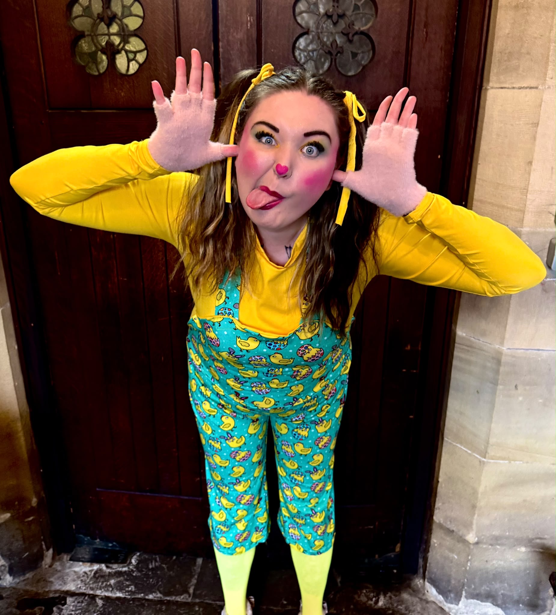 A smiling party host in yellow sleeves and duck-print dungarees