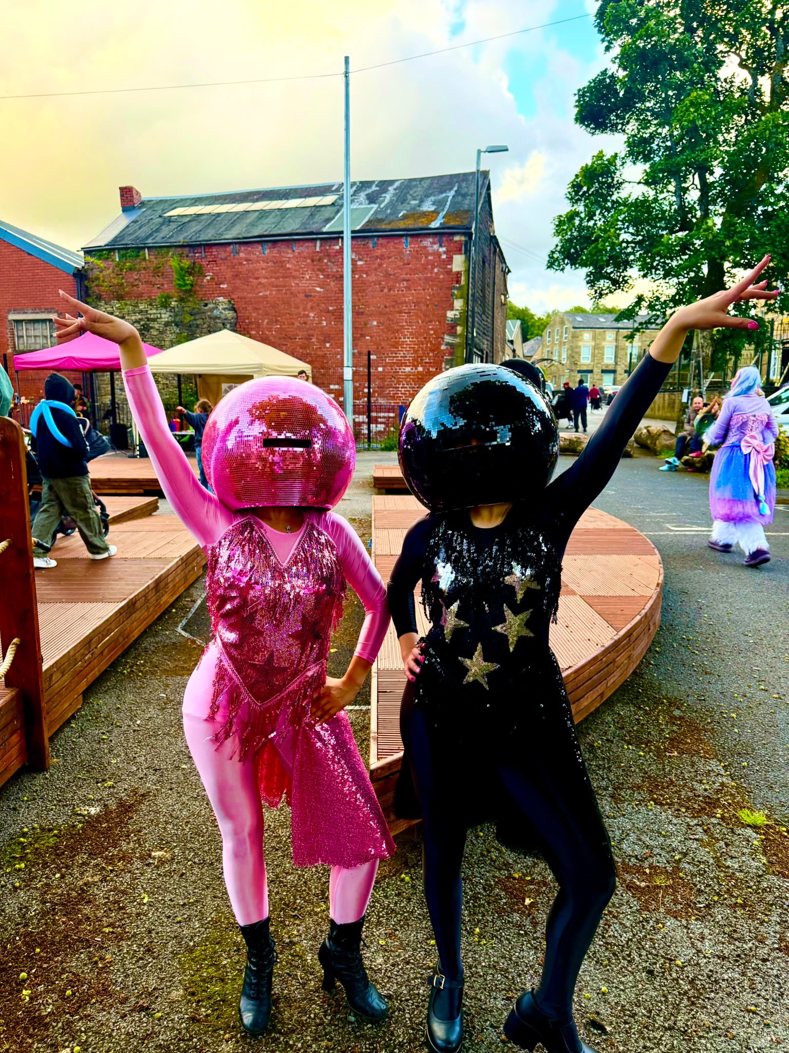 Pink and black superhero characters greeting the camera at an outdoor event
