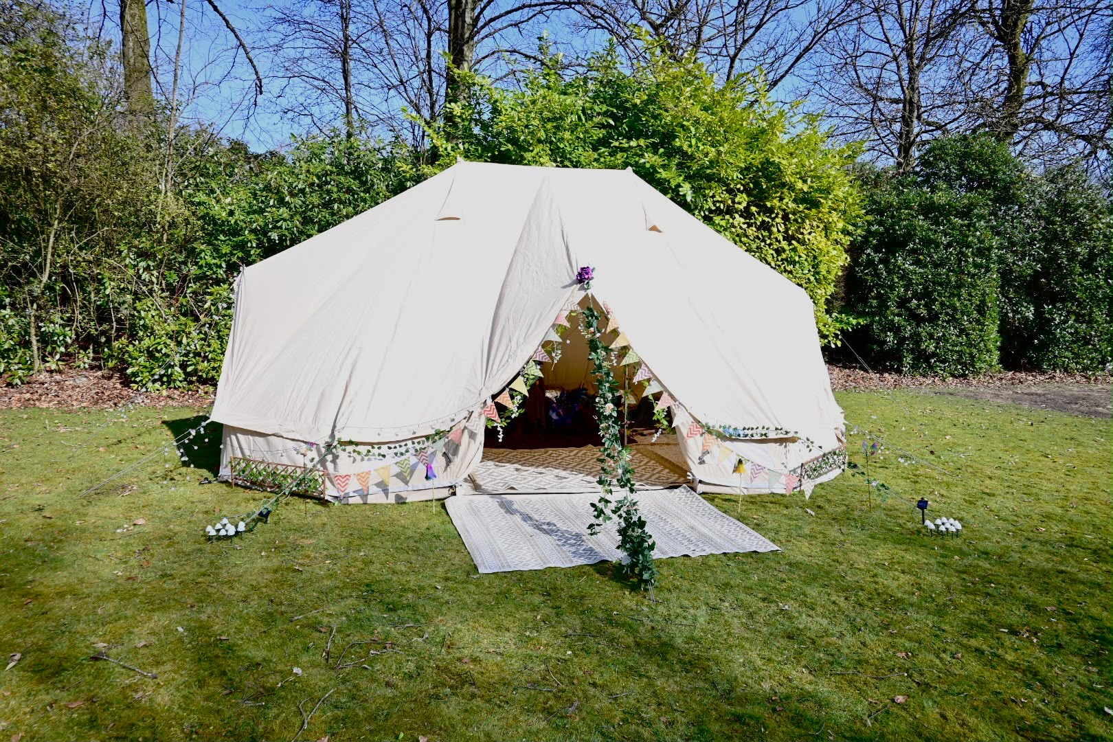 A flower-trimmed bell tent set up on a sunny lawn